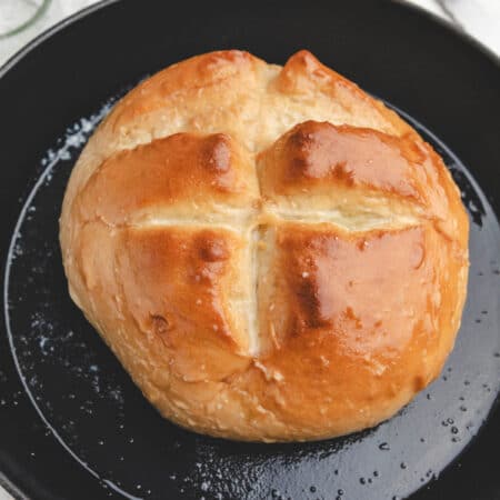 A loaf of baked skillet bread brushed with butter and sprinkled with salt.