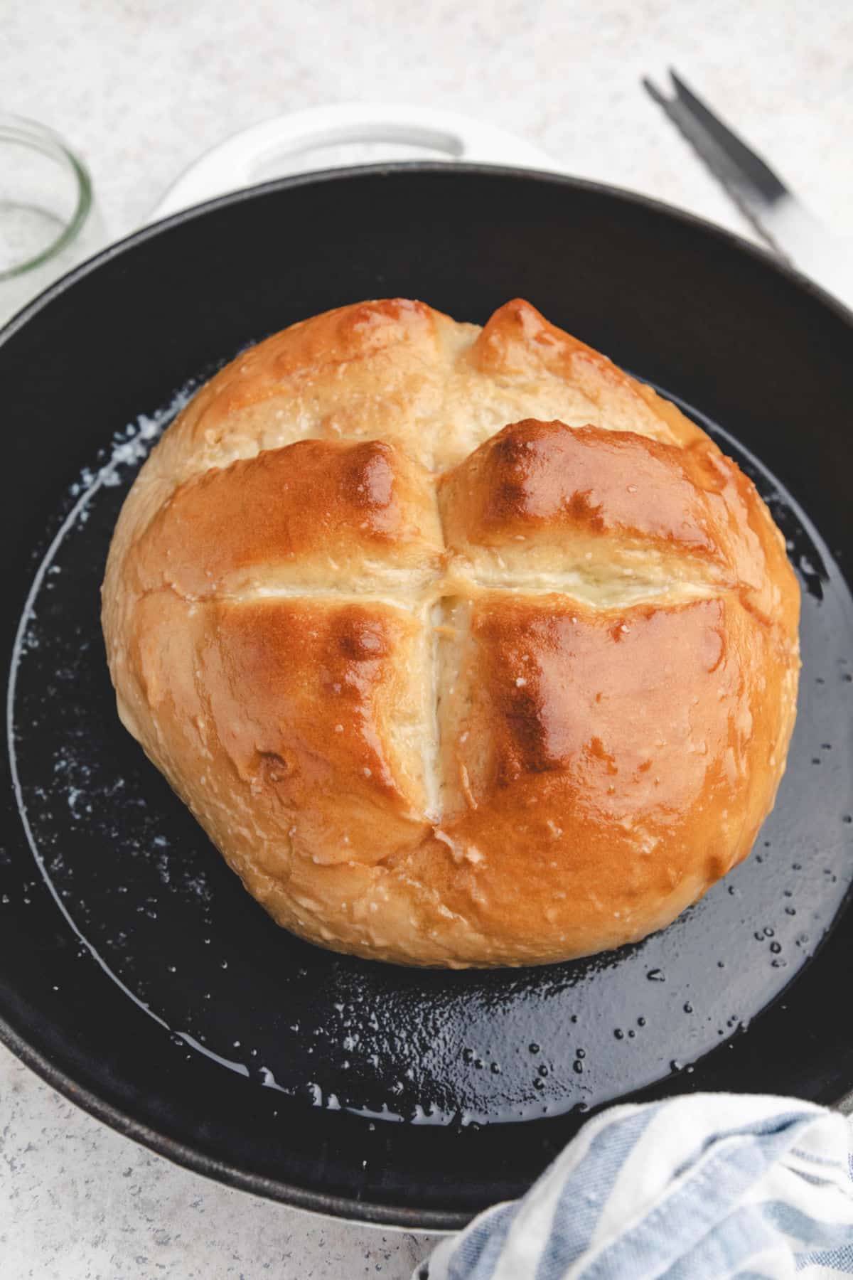 A loaf of baked skillet bread brushed with butter and sprinkled with salt. 