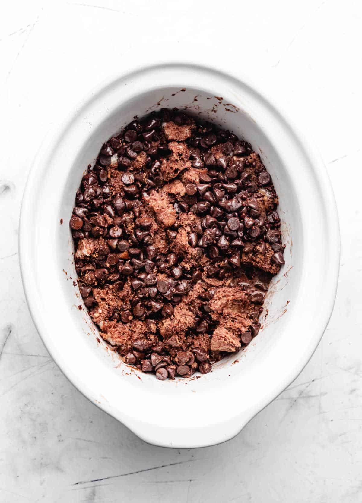 Chocolate mixture poured over bread cubes in a slow cooker.