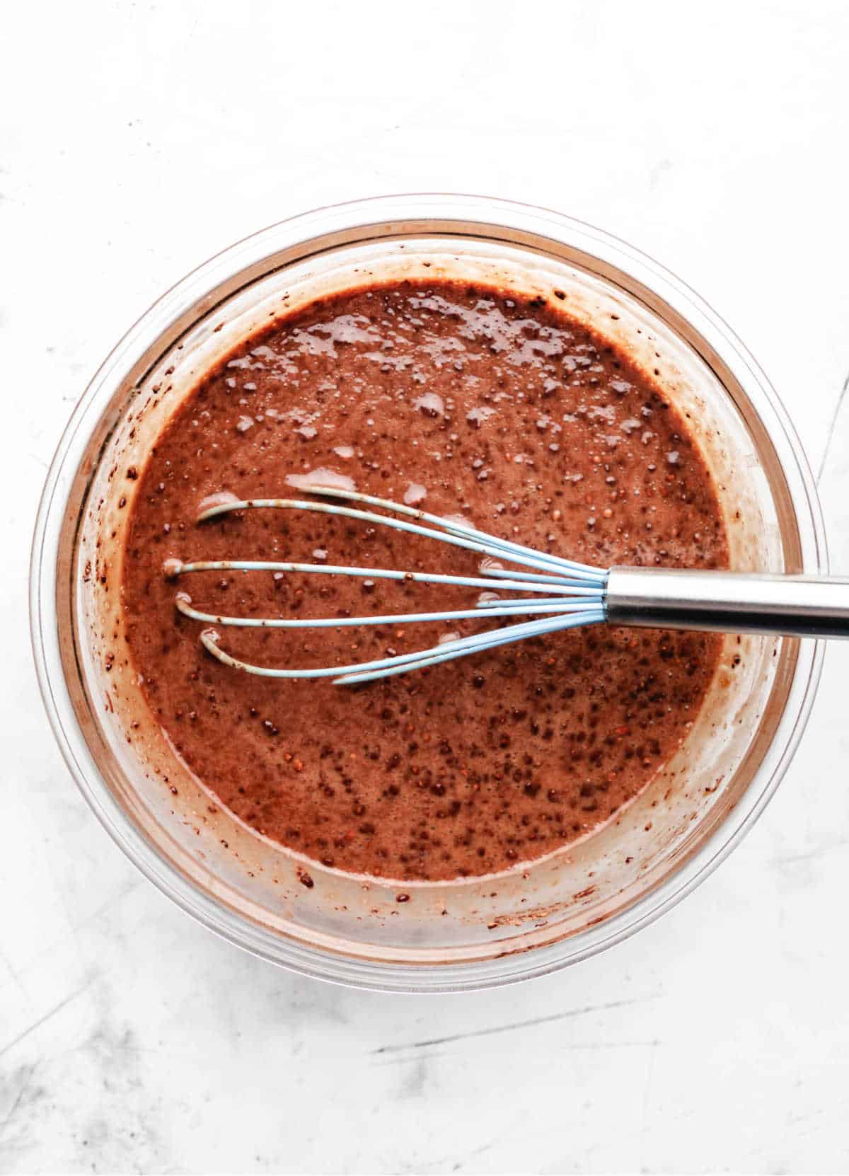 Chocolate mixture in a glass mixing bowl for chocolate bread pudding.