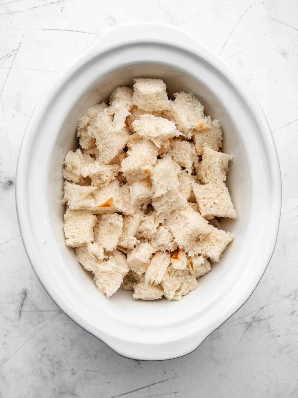 Cubes of bread in a slow cooker insert. 