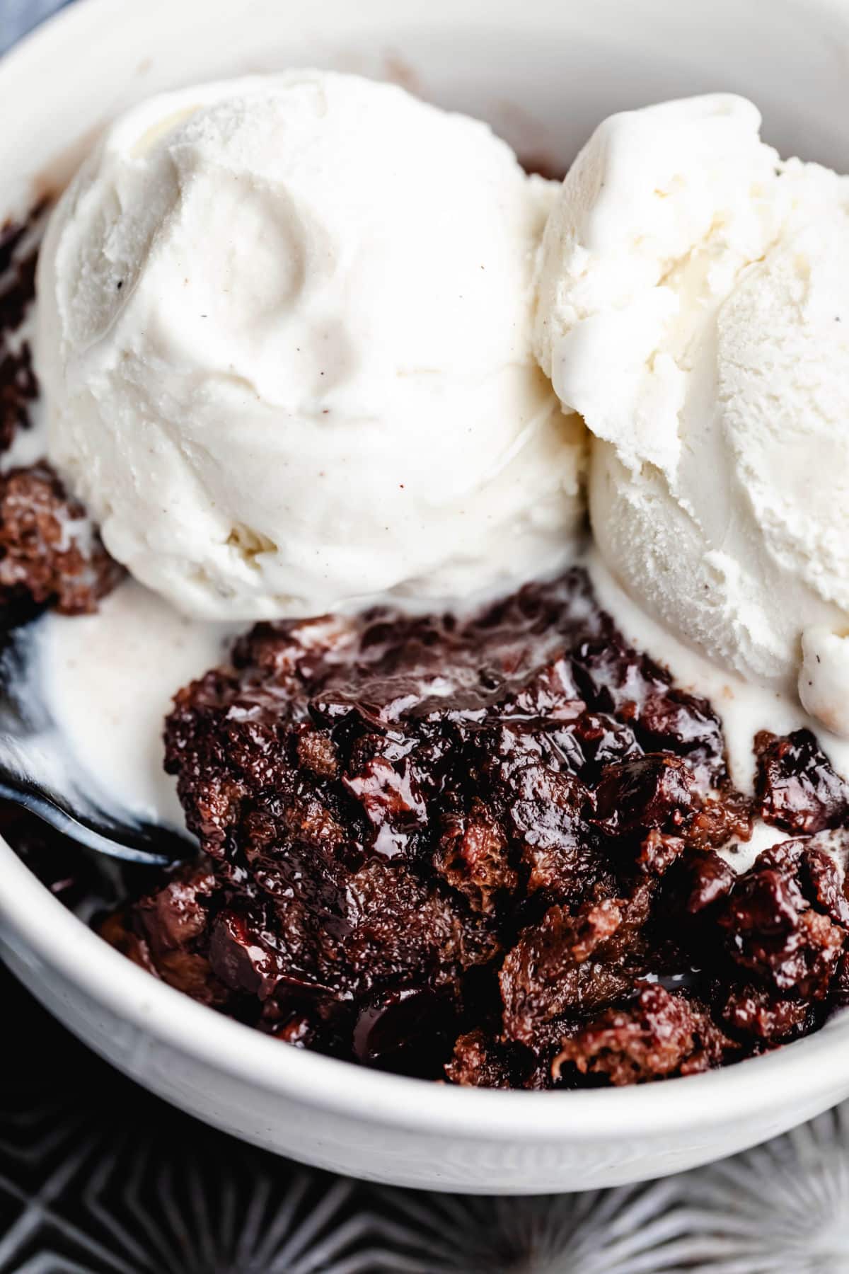 Two scoops of vanilla ice cream on top of a dish of chocolate bread pudding.