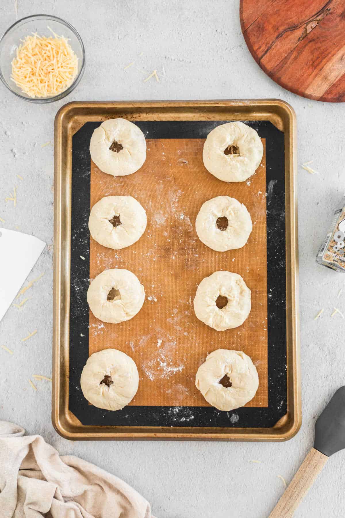 Eight balls of bagel dough with a hole in the middle of each ball. 