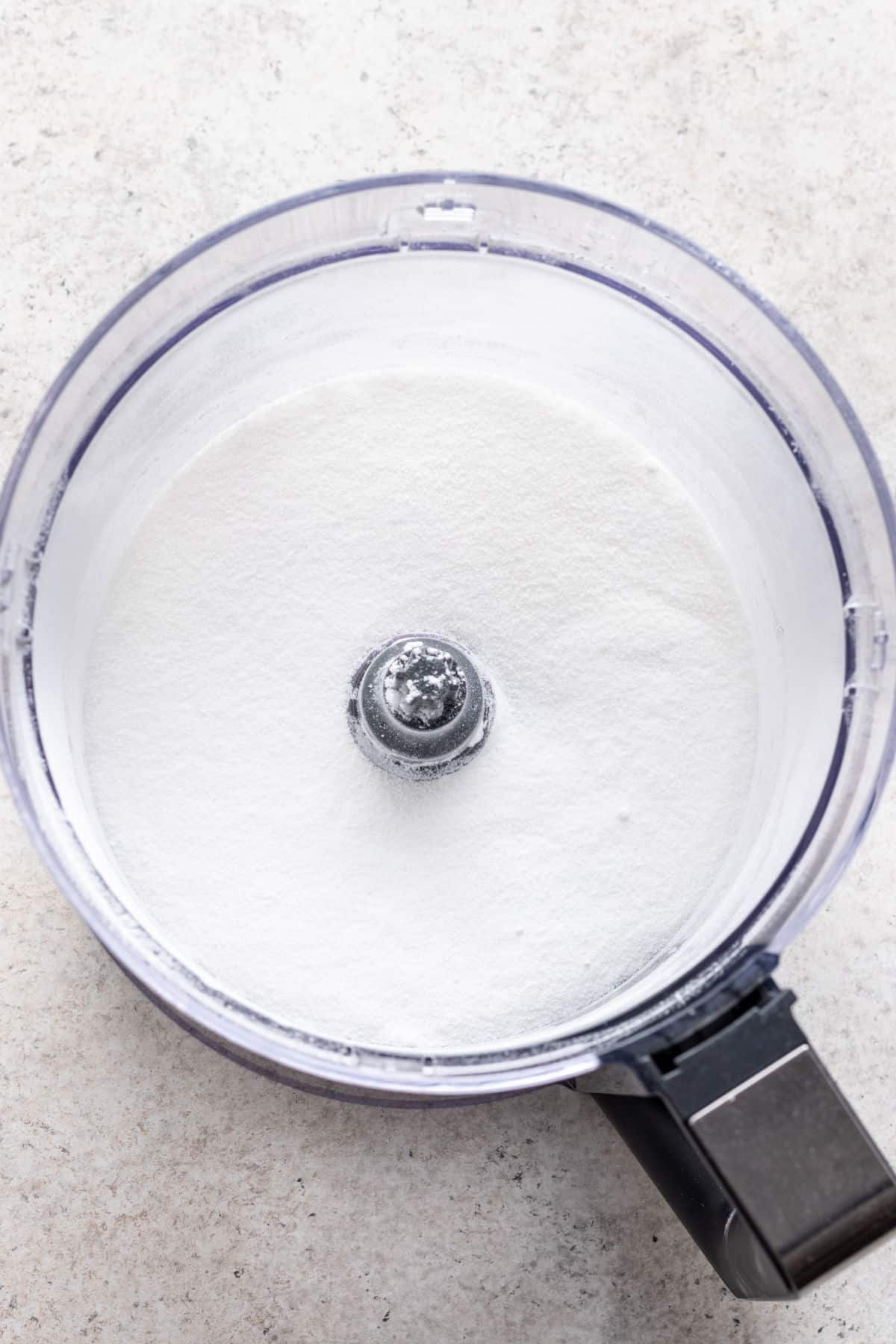A food processor holding granulated sugar.