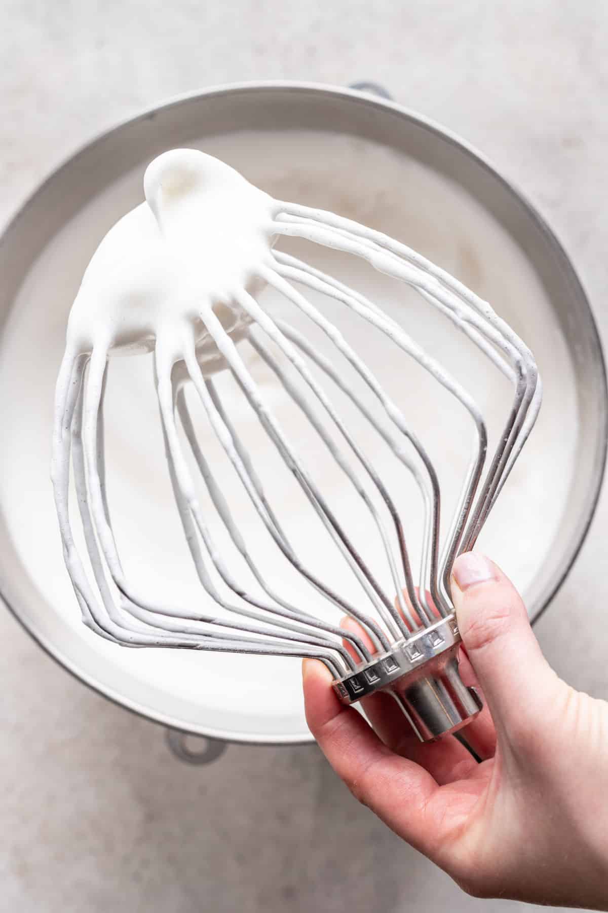 A whisk attachment with beaten egg white drooping over.