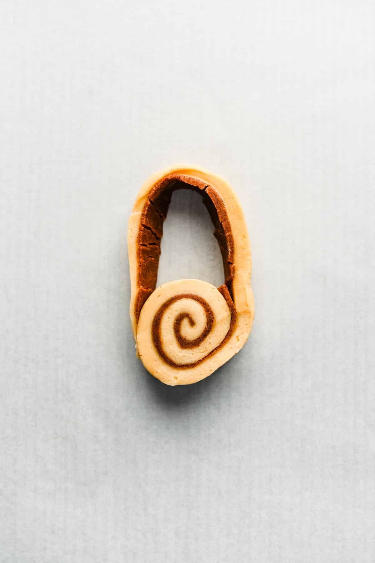A cinnamon roll with a loop of dough attached to it. 