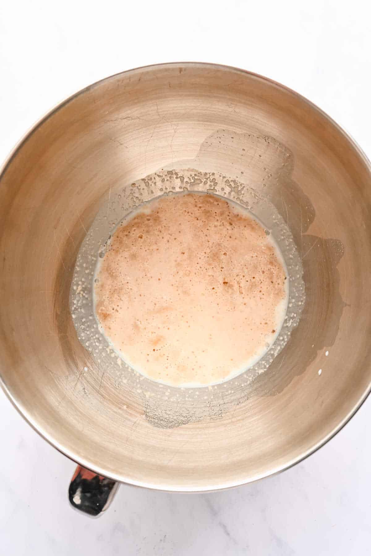 Yeast proofing in a silver mixing bowl.