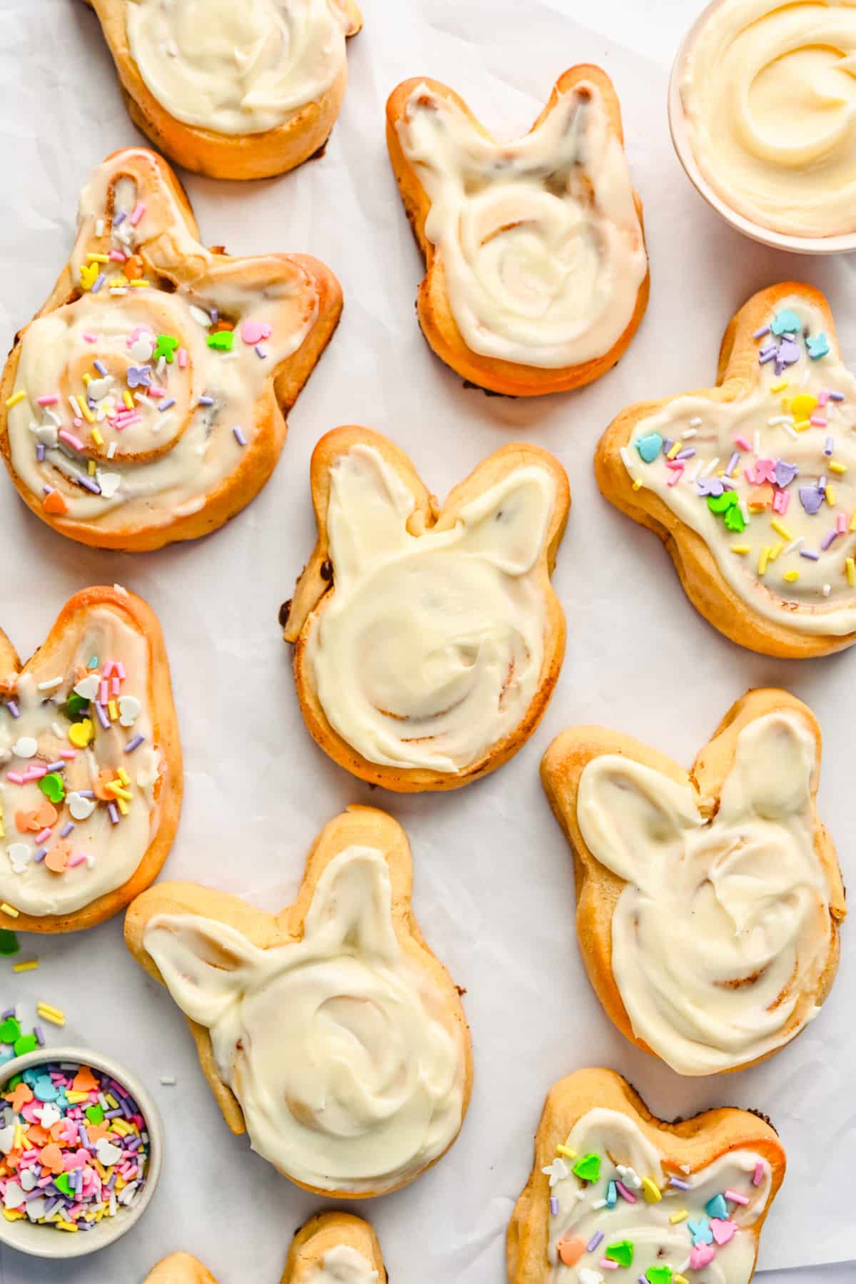 Bunny cinnamon rolls next to a dish of Easter sprinkles.
