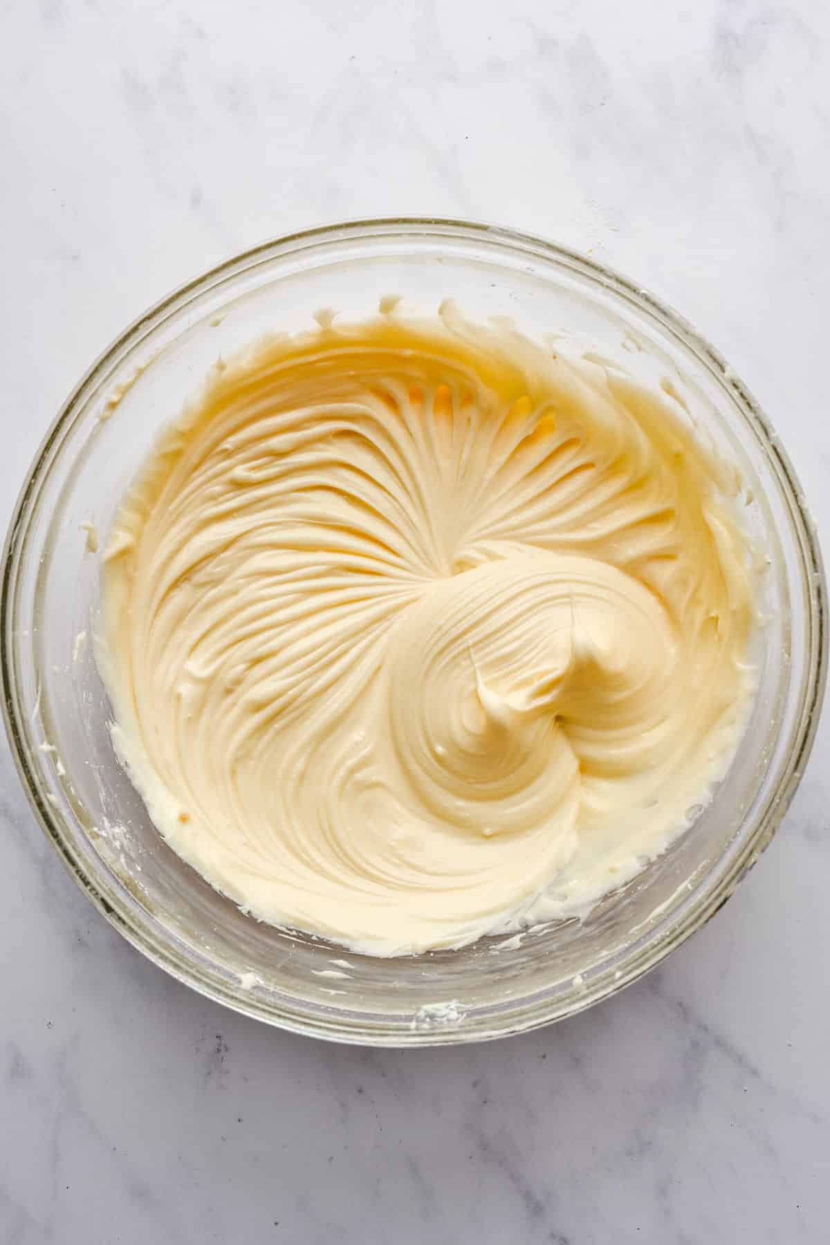 Cream cheese frosting in a glass mixing bowl. 