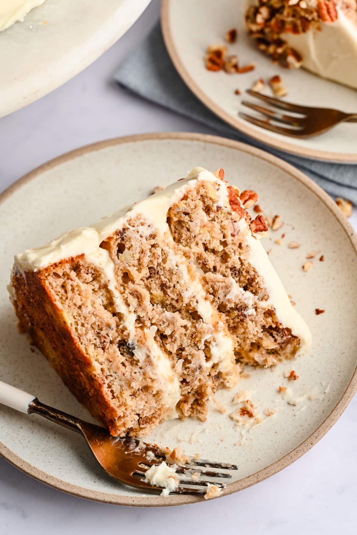 A slice of hummingbird cake on a plate with a bite missing. 