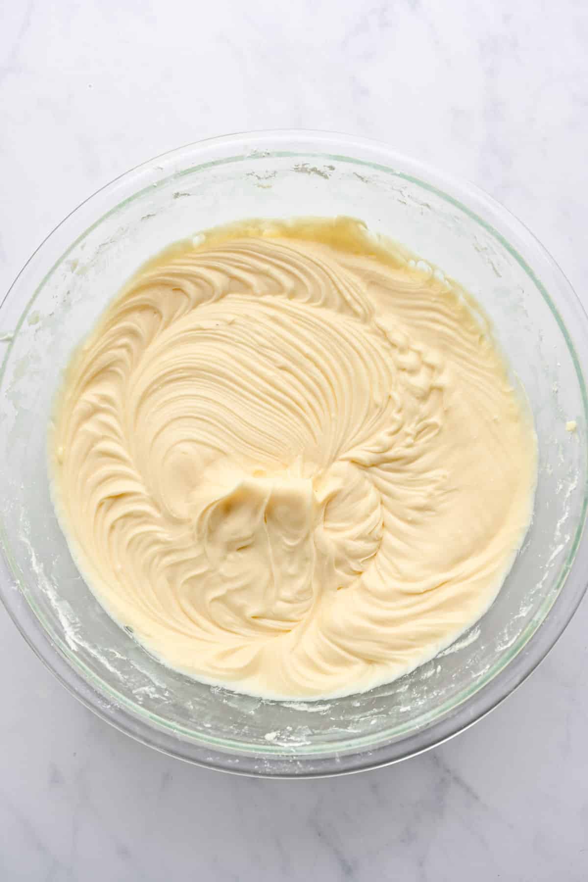 Cream cheese frosting in a glass mixing bowl.