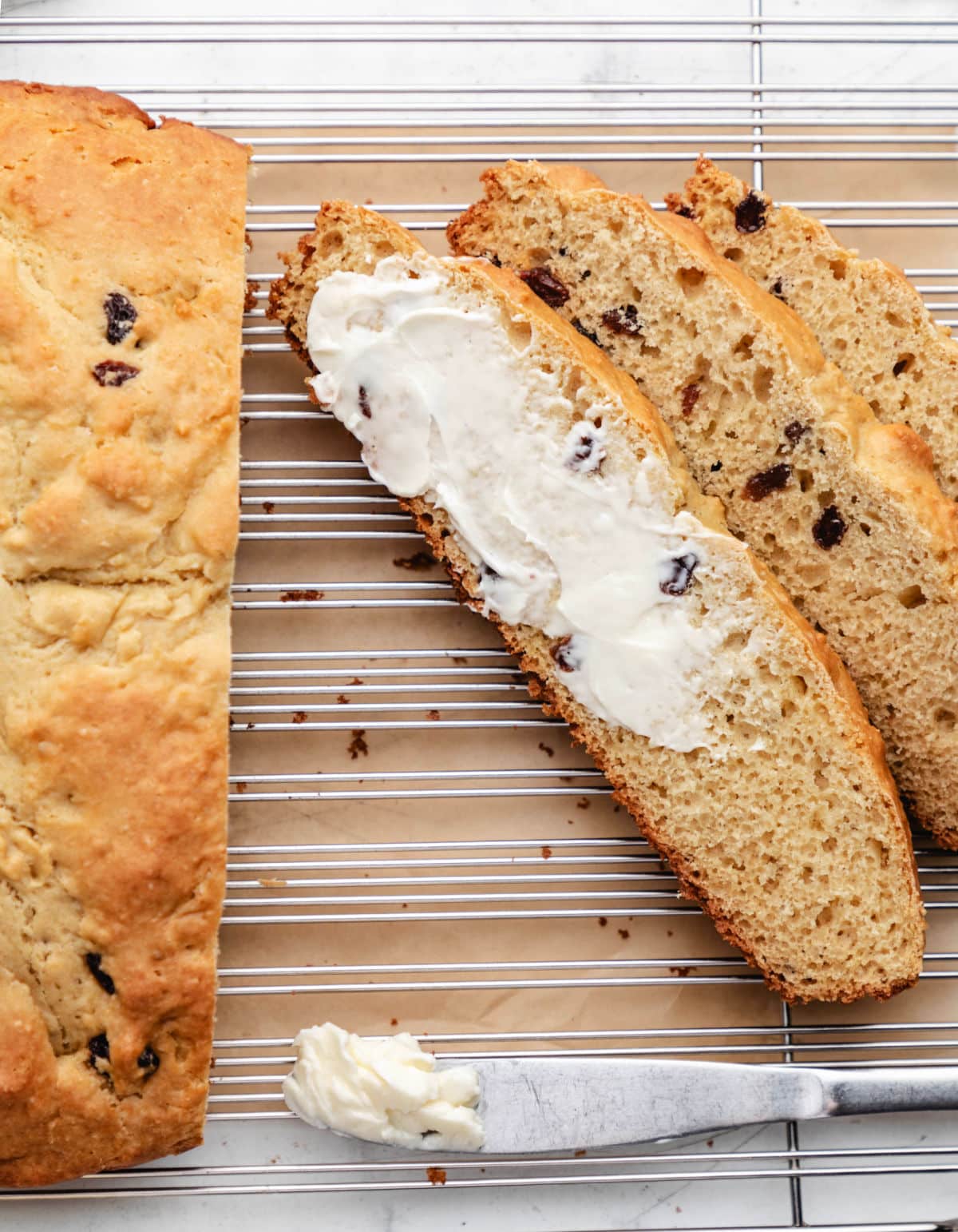 A slice of half-buttered Irish soda bread leaning against two other slices. 