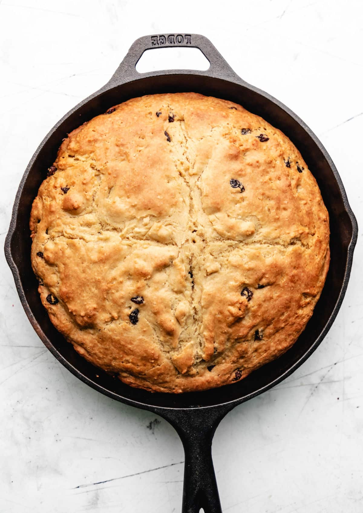 A baked loaf of Irish soda bread in a cast iron skillet.