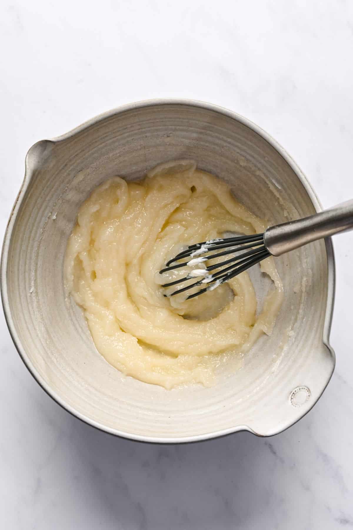 Icing for lemon loaf cake in a mixing bowl with a whisk in it. 