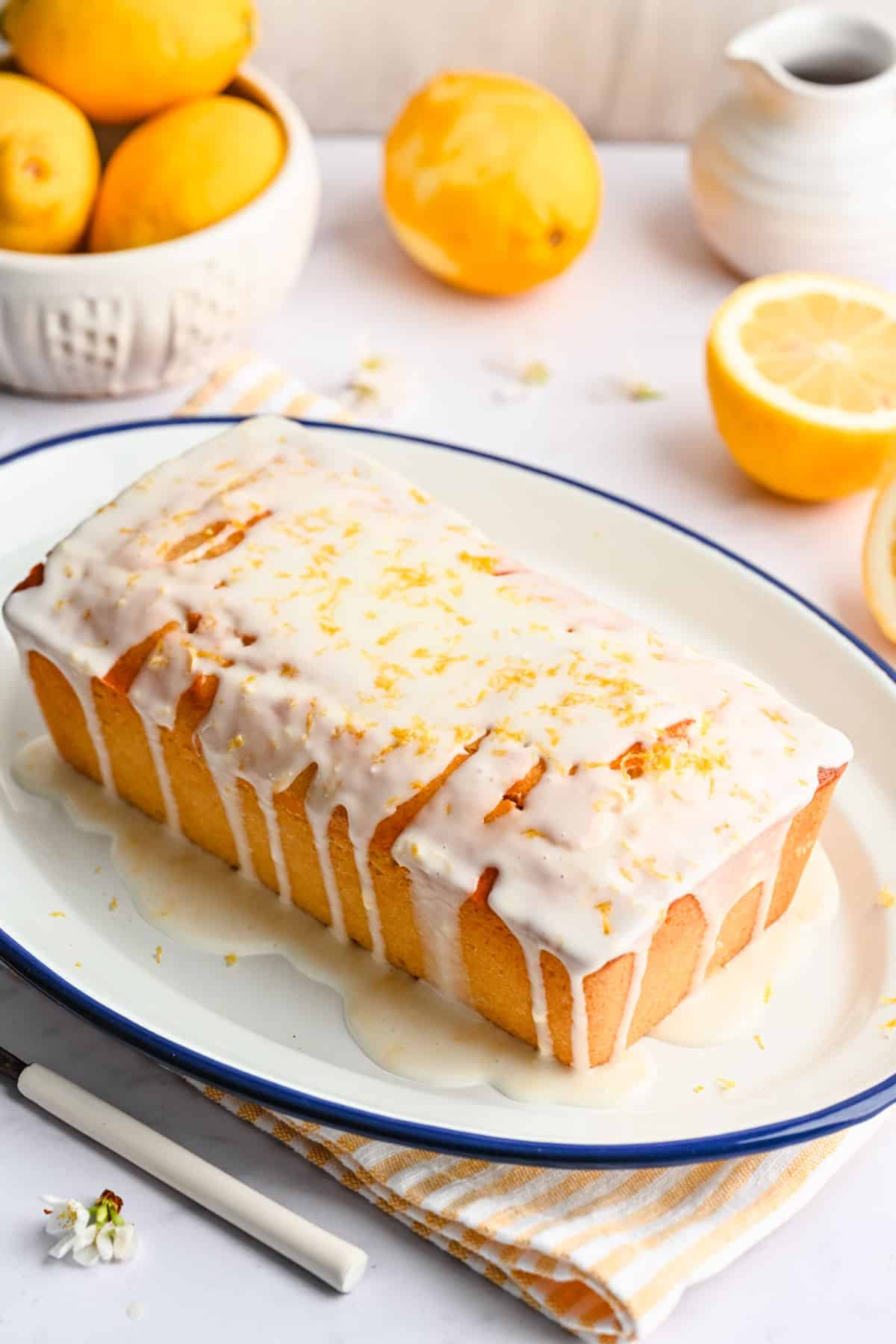 A whole lemon loaf cake topped with icing and fresh lemon zest.