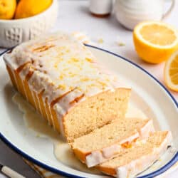 Lemon loaf cake on a plate with two pieces sliced.