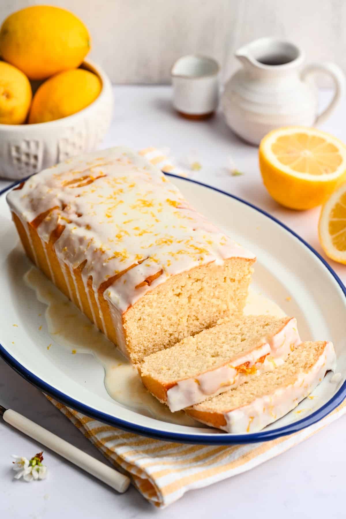 Lemon loaf cake on a plate with two pieces sliced.