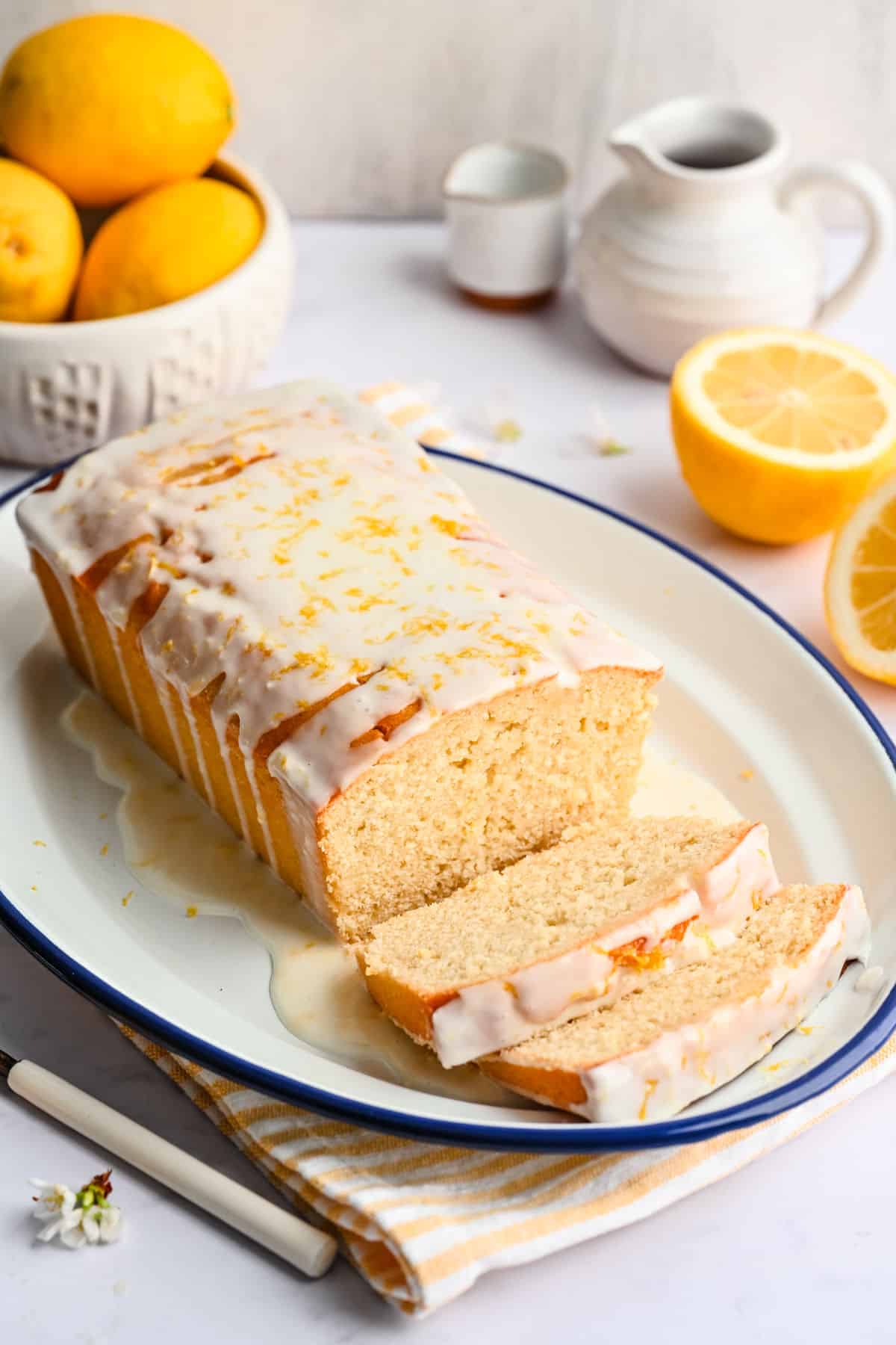 Lemon loaf cake on a plate with two pieces sliced. 