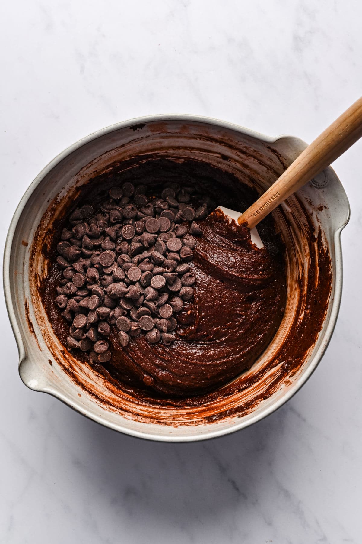 Chocolate chips on top of brownie batter in a mixing bowl.