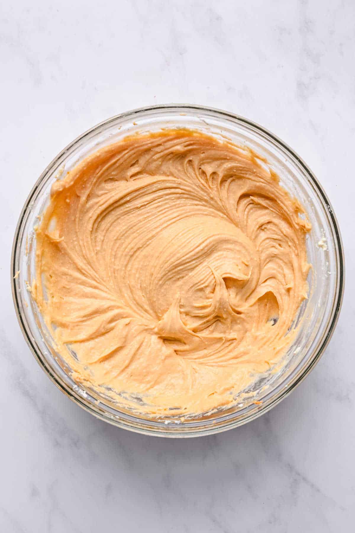 Peanut butter and sugar mixed into cream cheese in a mixing bowl. 