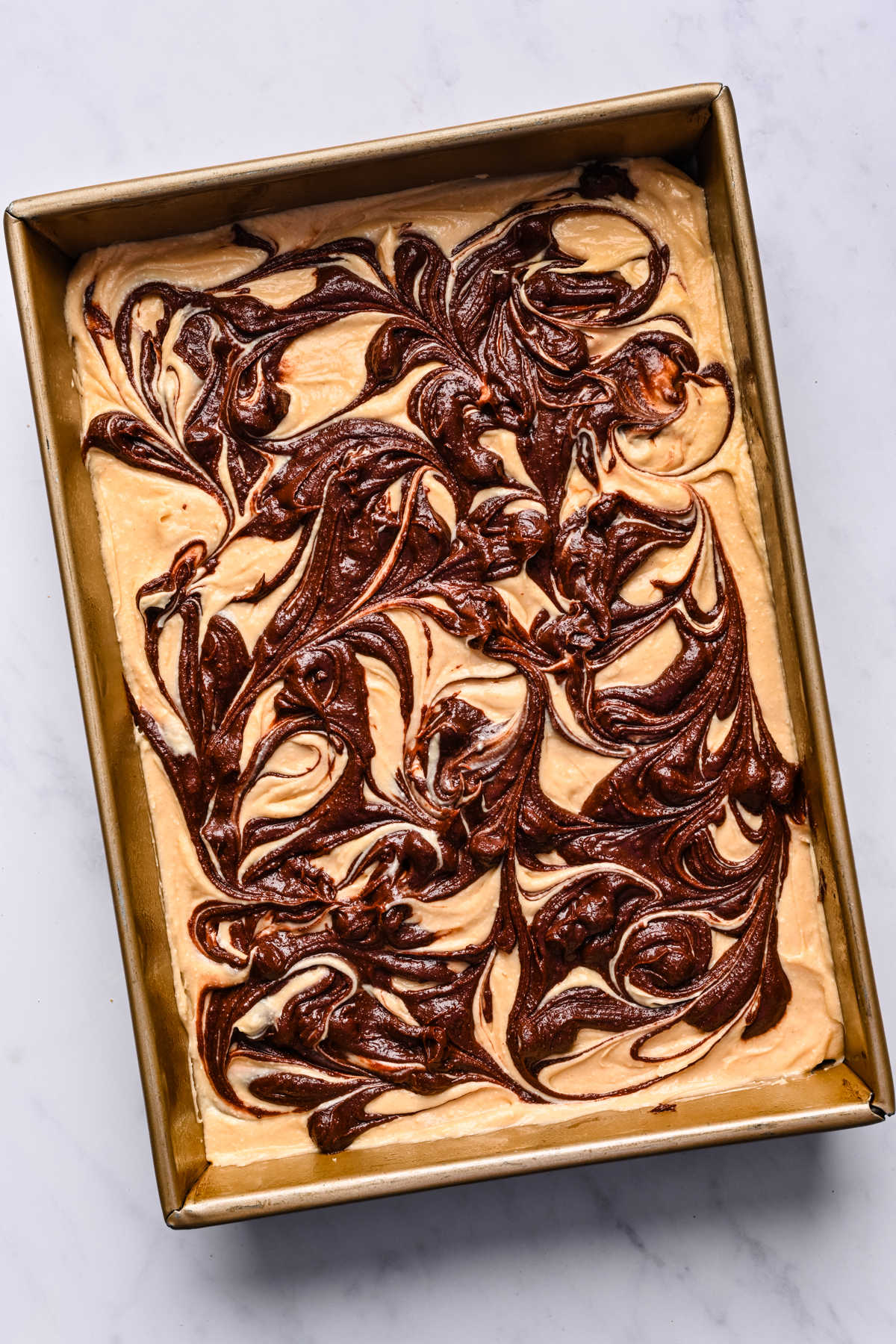 Swirled brownie and peanut butter batter in a metal baking pan.