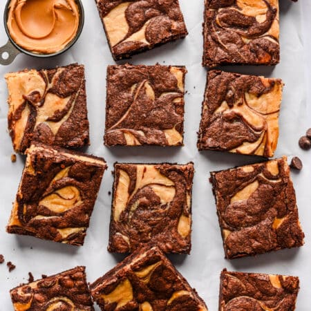 Peanut butter brownies next to a measuring cup full of peanut butter.