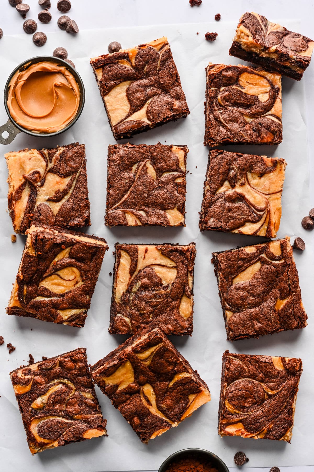 Peanut butter brownies next to a measuring cup full of peanut butter.