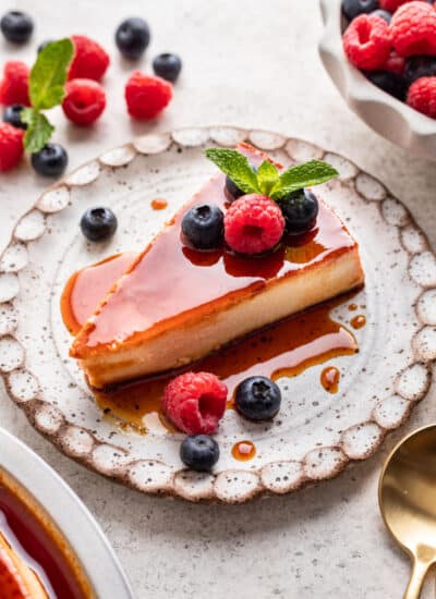 A slice of flan de queso on a speckled pottery plate.