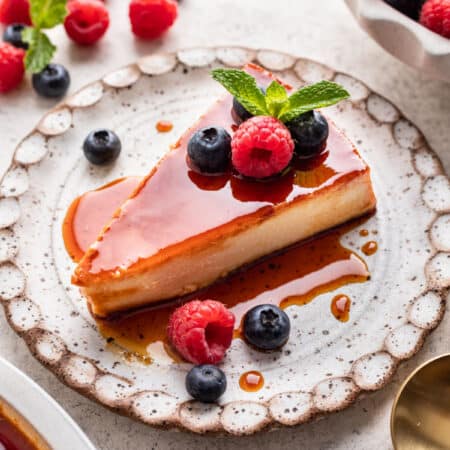 A slice of flan de queso on a speckled pottery plate.