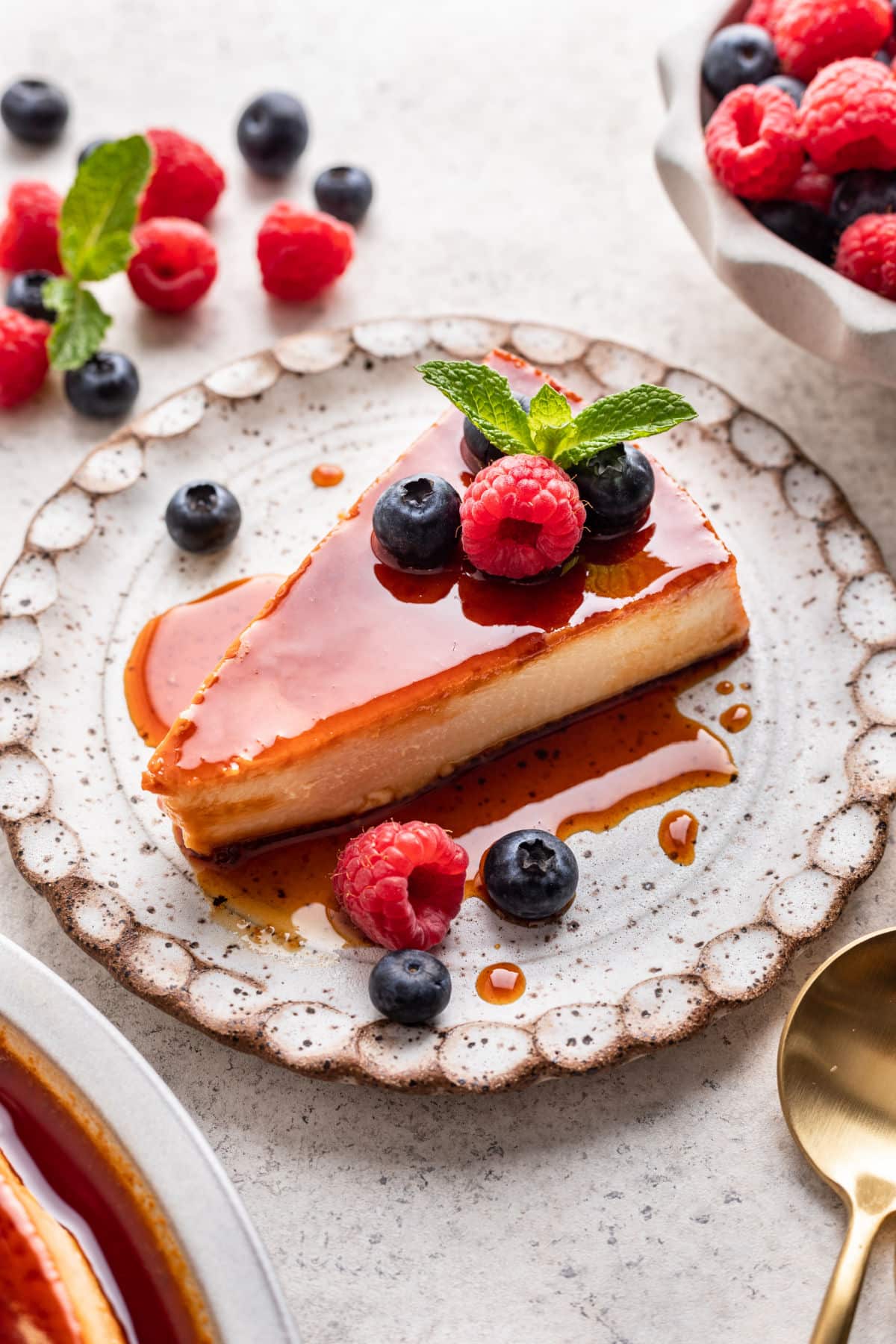 A slice of flan de queso on a speckled pottery plate.