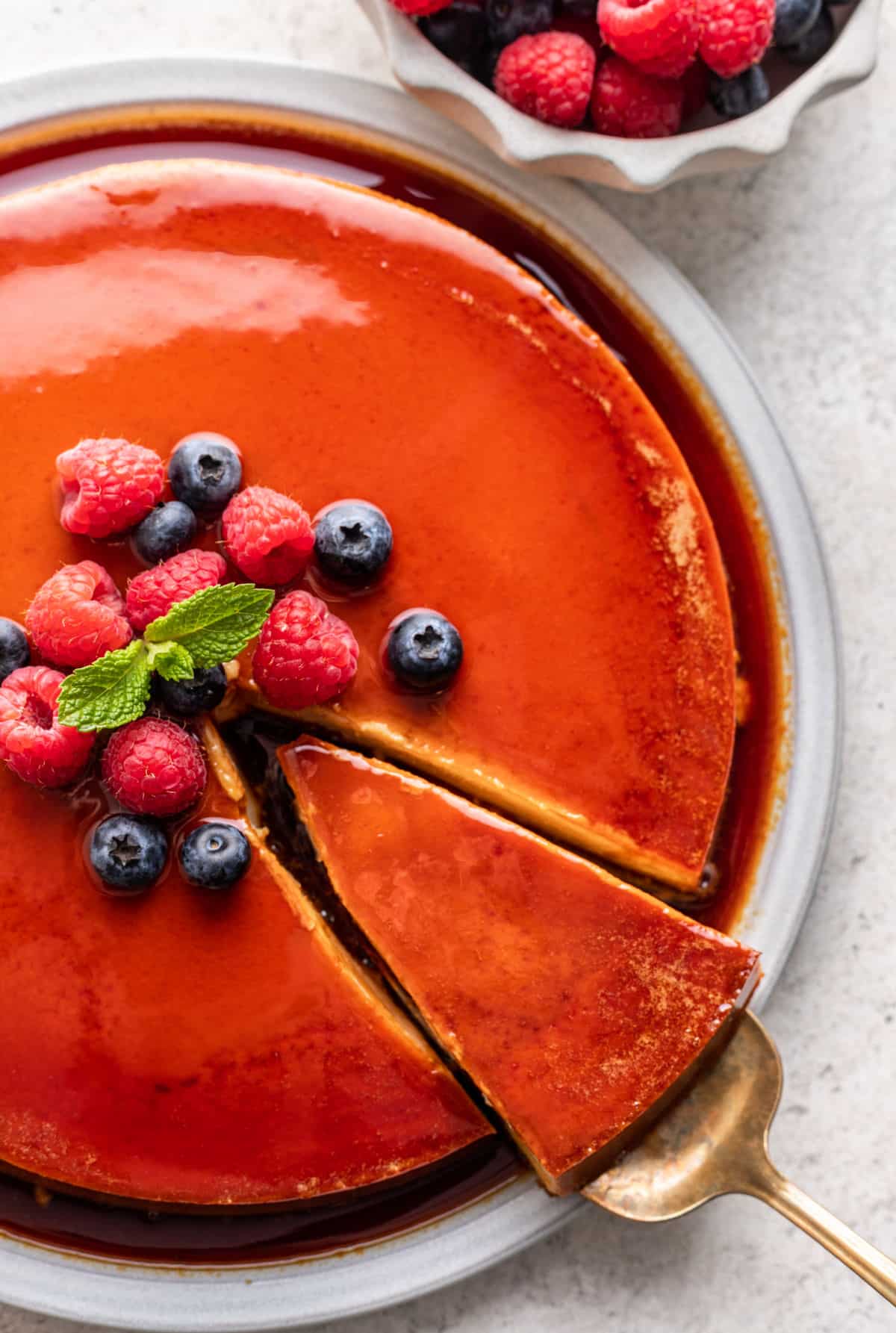 A silver cake holder removing a slice of flan.