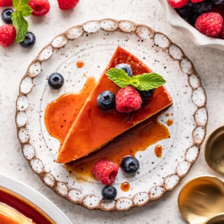 A slice of flan de queso topped with fresh berries.