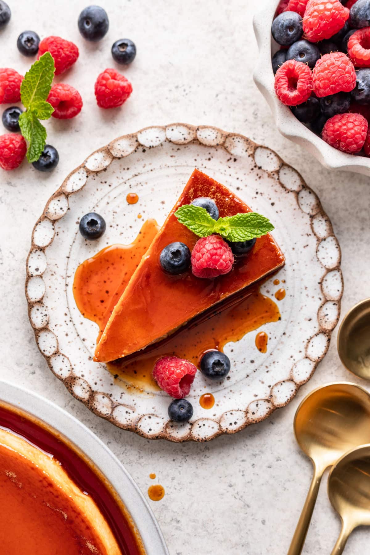 A slice of flan de queso topped with fresh berries. 