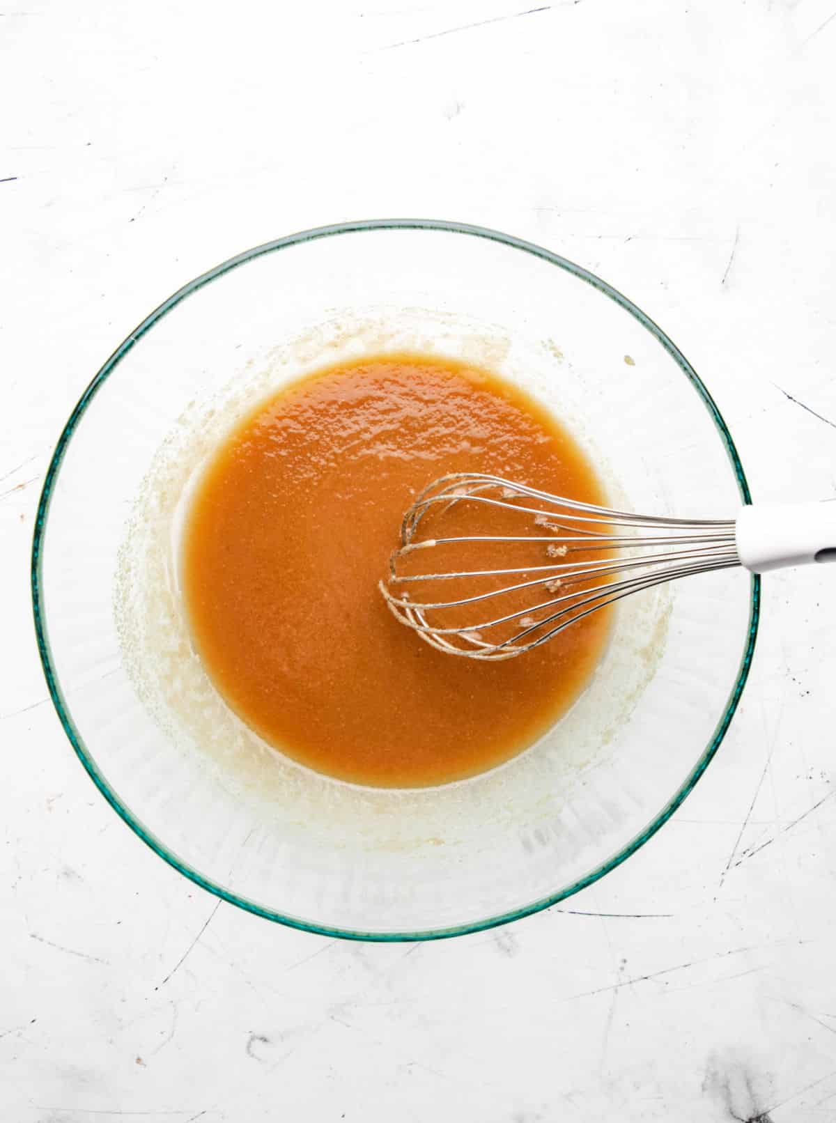 Brown sugar whisked into melted butter in a glass mixing bowl. 