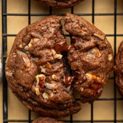 A German chocolate cookie broken in half on a wire cooling rack.