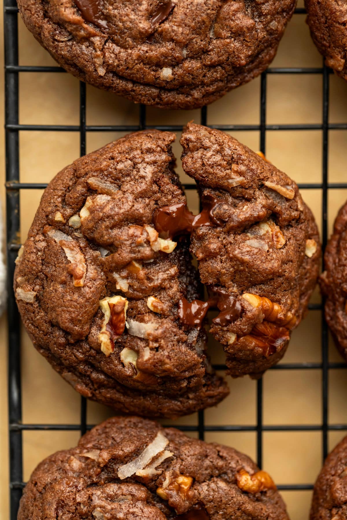 A German chocolate cookie broken in half on a wire cooling rack.