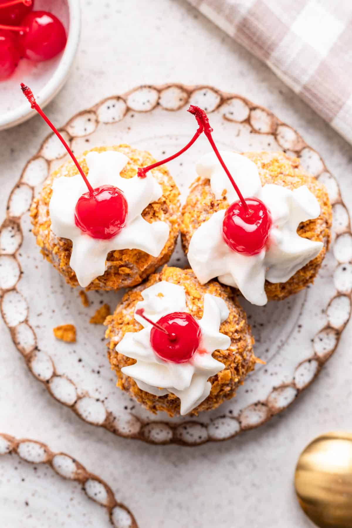 Three scoops of no fry fried ice cream topped with whipped cream and a cherry.