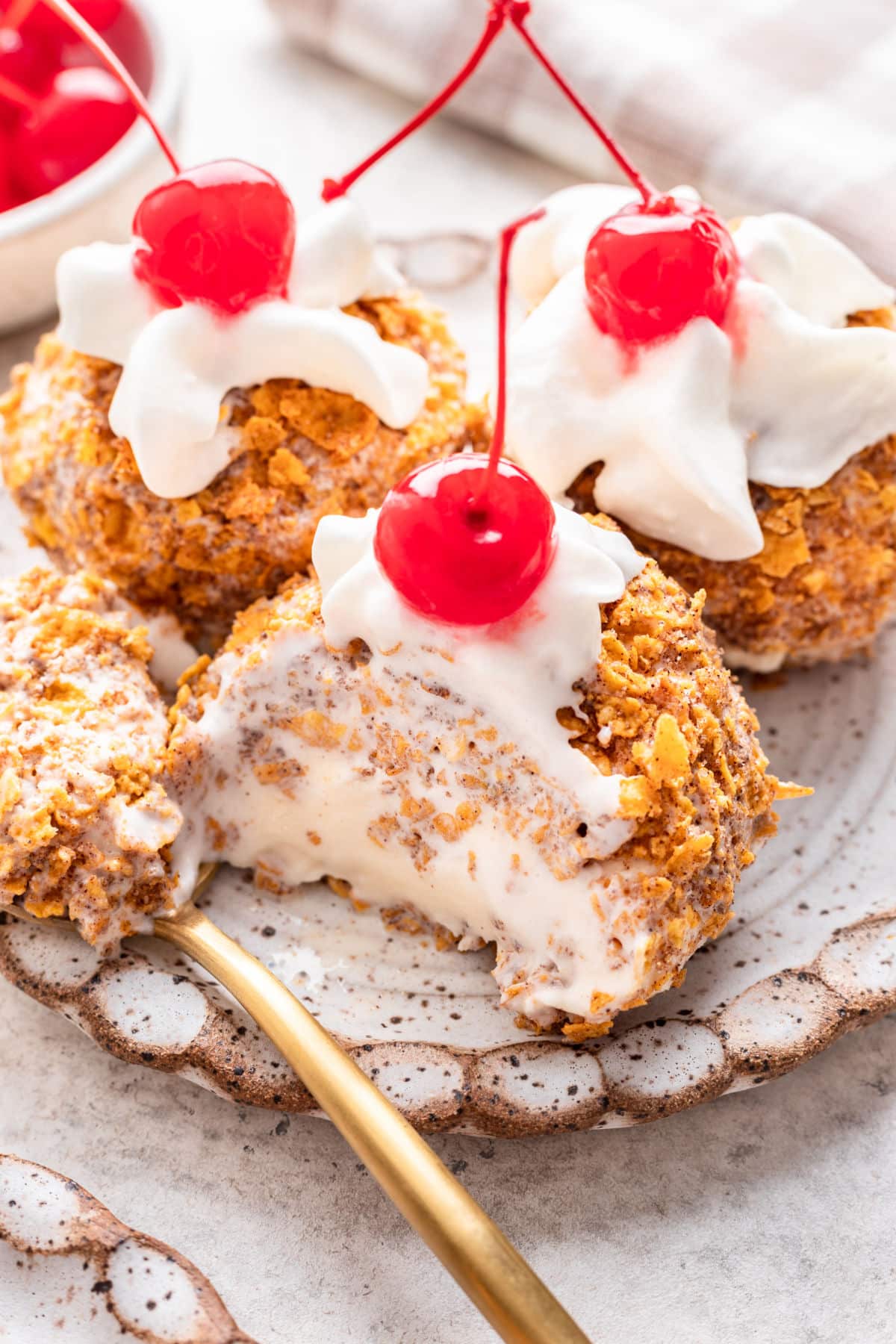 A spoon holding a bite of no fry fried ice cream next to the scoop.