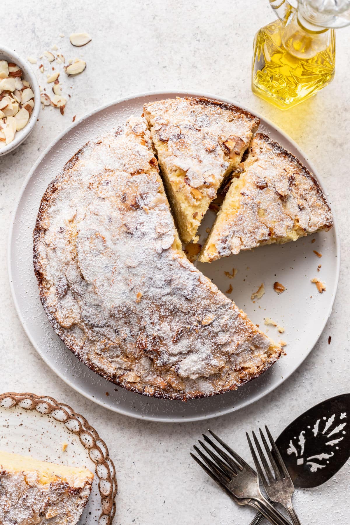 An olive oil cake with a slice missing and two slices cut.