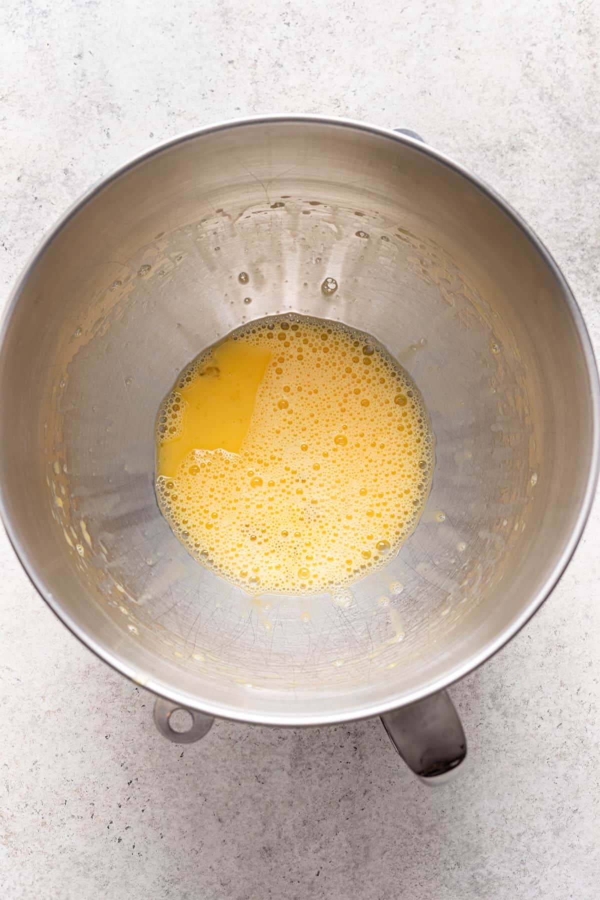 Eggs whisked until foamy in a silver mixing bowl.
