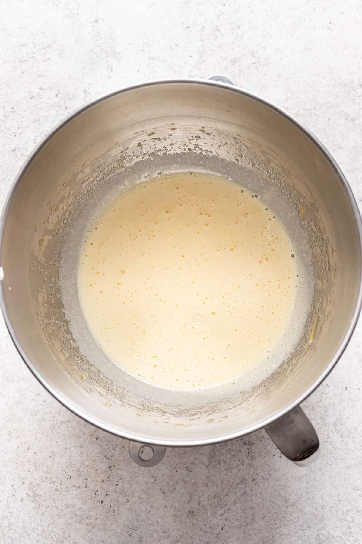 Eggs and sugar beaten until pale in a silver mixing bowl.