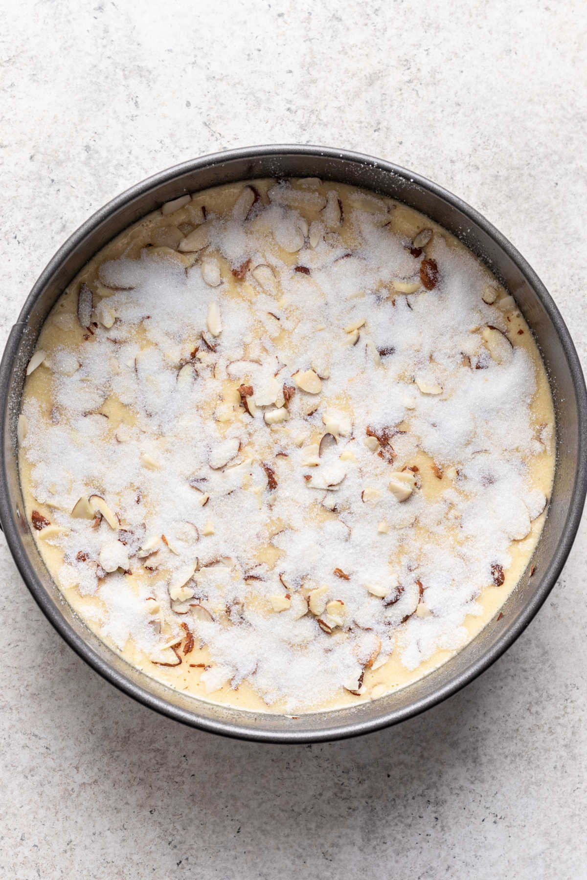 Sugar and almonds on top of olive oil cake batter.