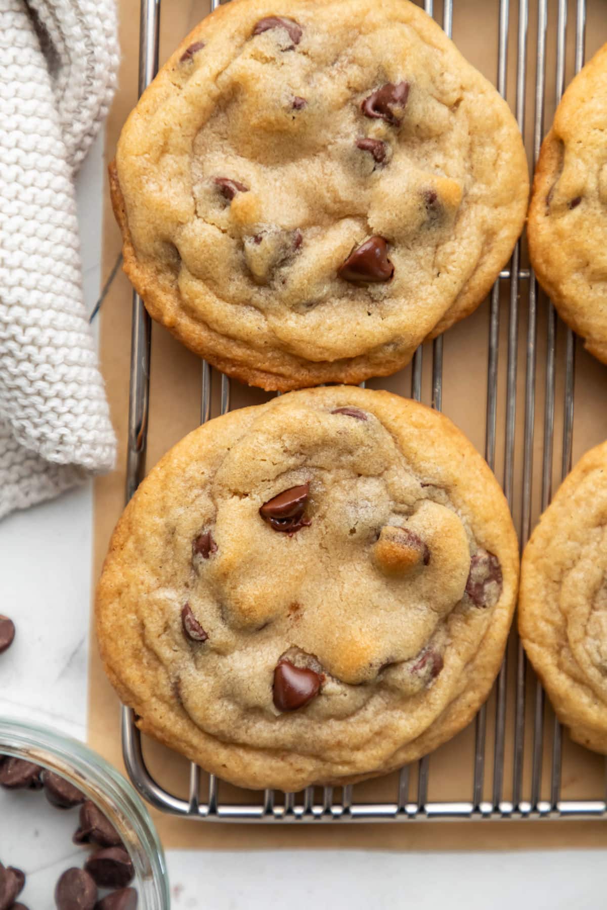 A row of bakery style chocolate chip cookies next to a dish of chocolate chips.