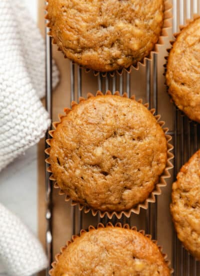 A row of banana muffins on a wire cooling rack.