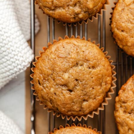 A row of banana muffins on a wire cooling rack.