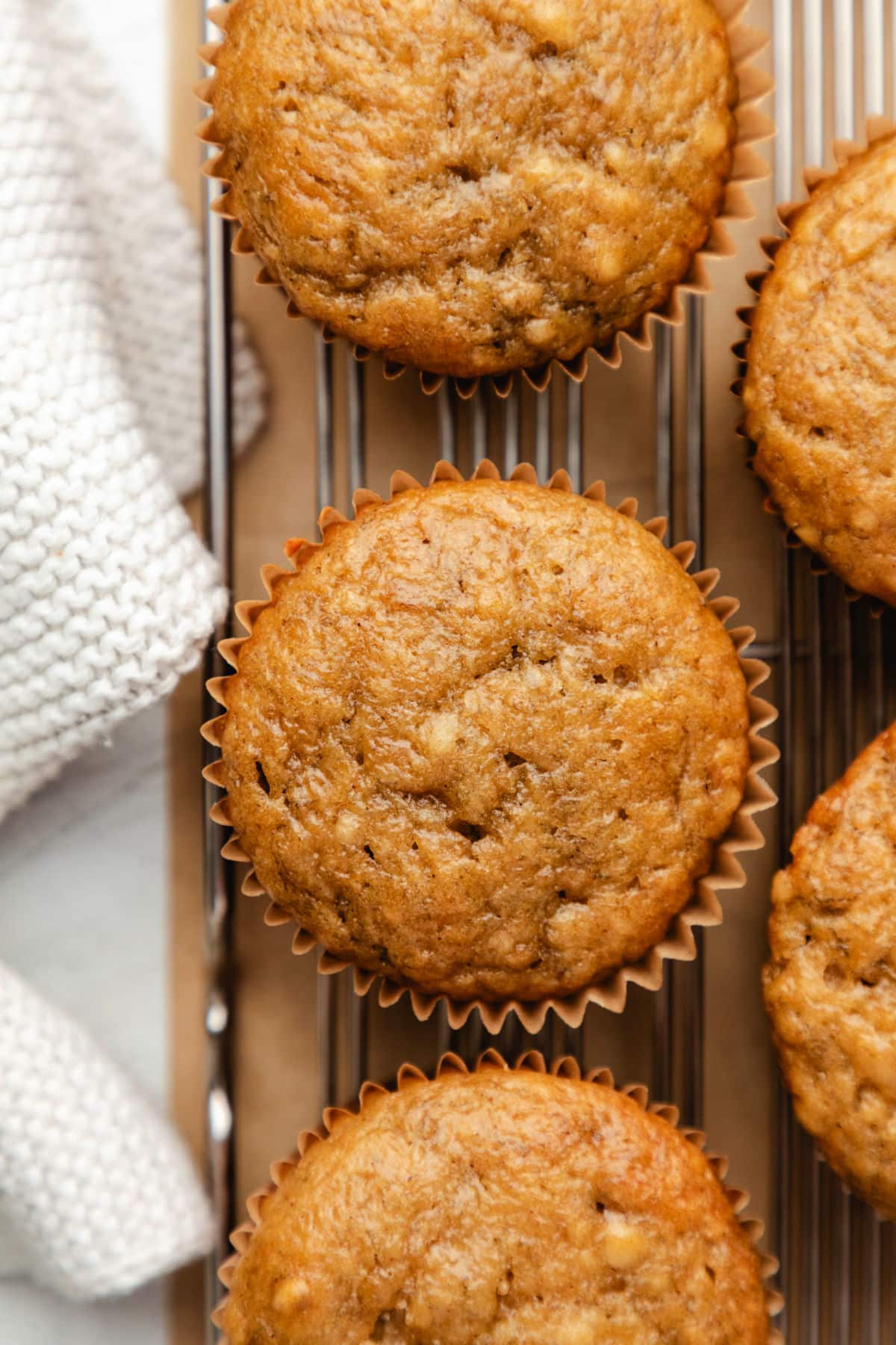 A row of banana muffins on a wire cooling rack.