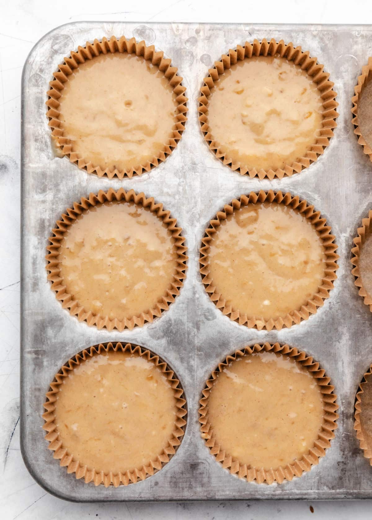 Banana muffin batter in a muffin tin.