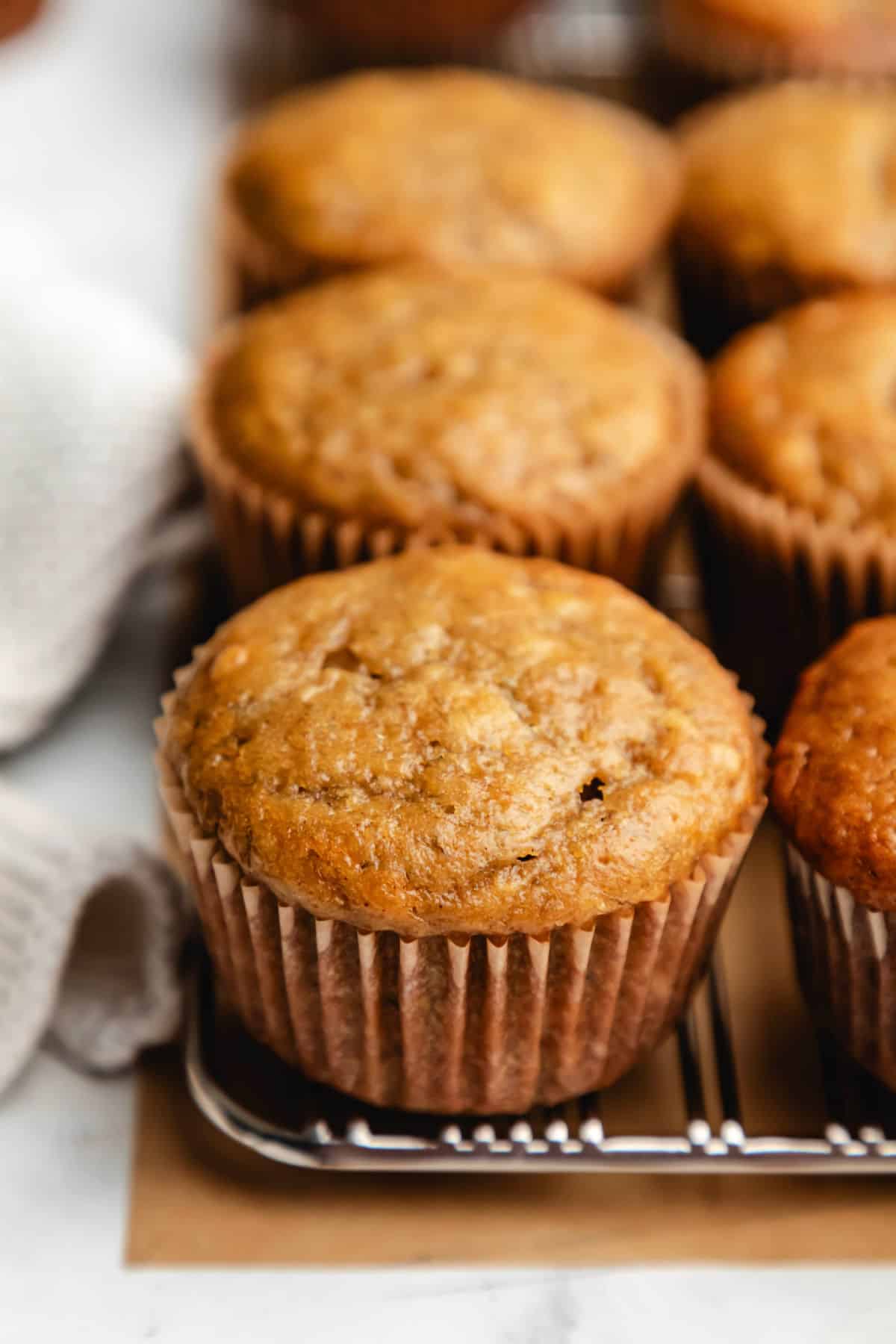 A row of banana muffins next to a cream napkin.