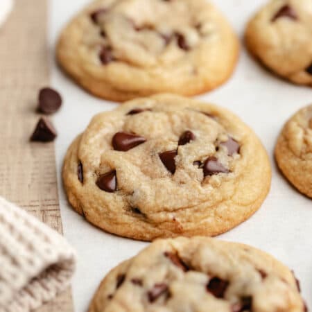 A row of easy chocolate chip cookies on a piece of white parchment paper.