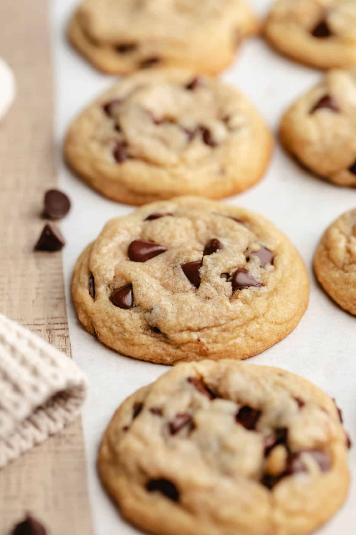 A row of easy chocolate chip cookies on a piece of white parchment paper. 